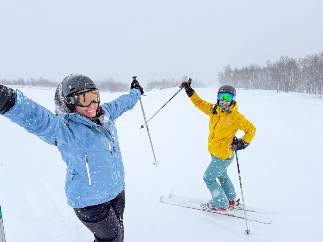 Women skiing on a snowy slope, snow-covered landscape in the background