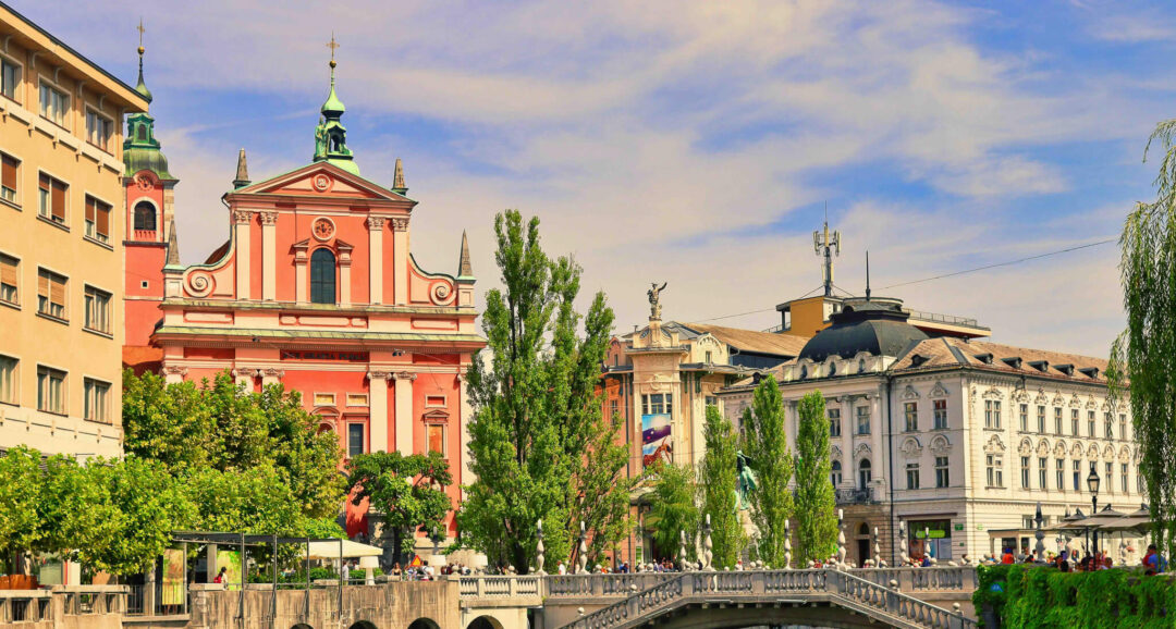 Pink baroque church and river bridge in Ljubljana, Slovenia under a blue evening sky