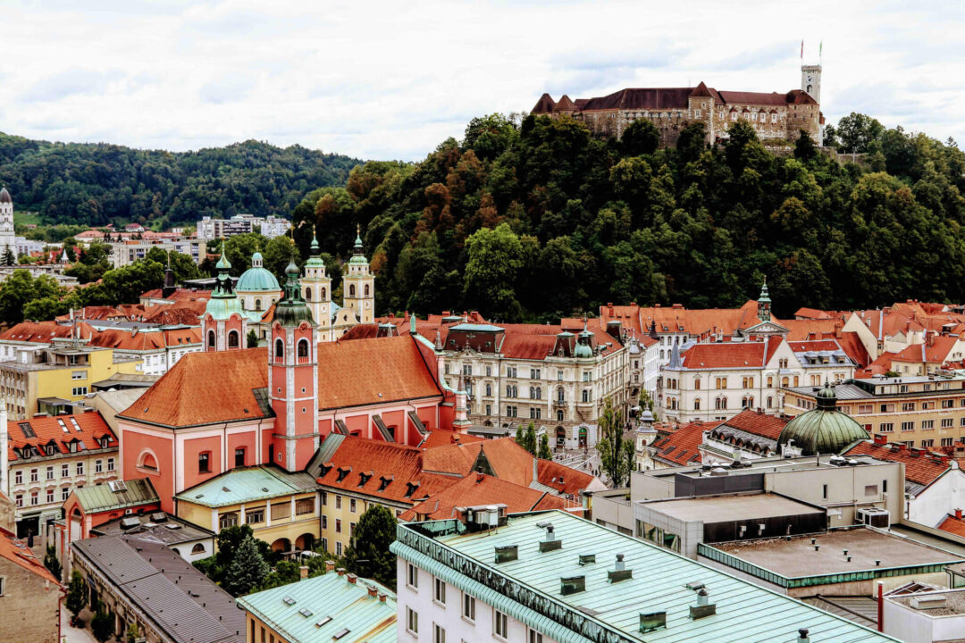 Ljubljana Castle above red-tiled rooftops and domes, aerial view of Ljubljana, Slovenia