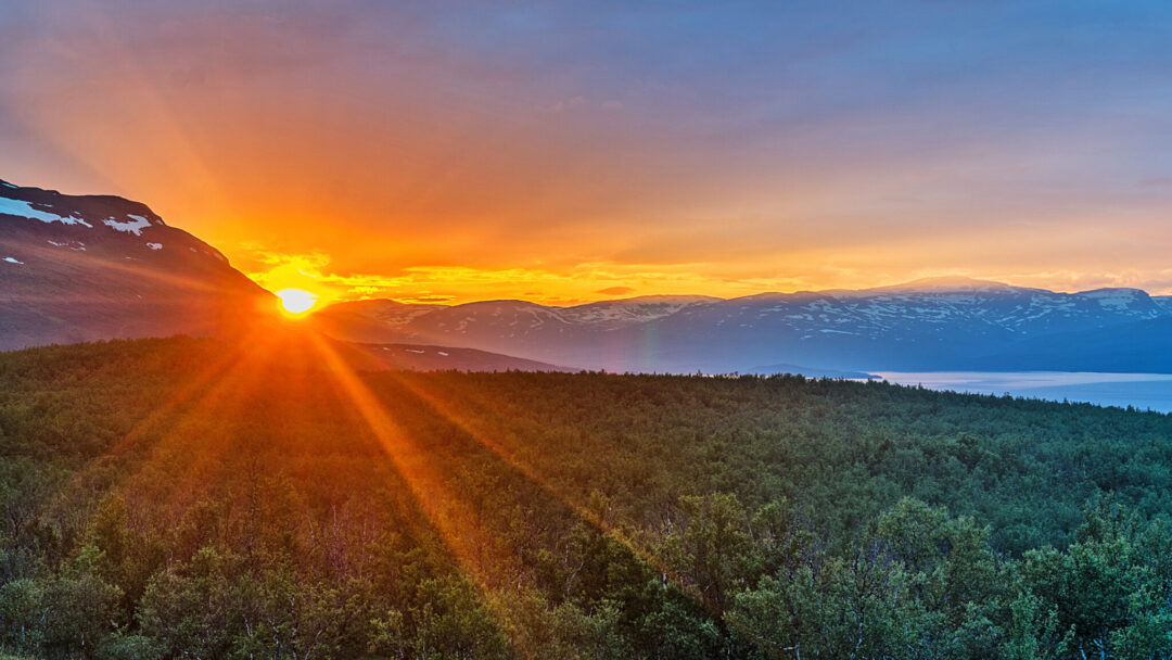 Sunrise over forested mountain valleys with low sun on the horizon