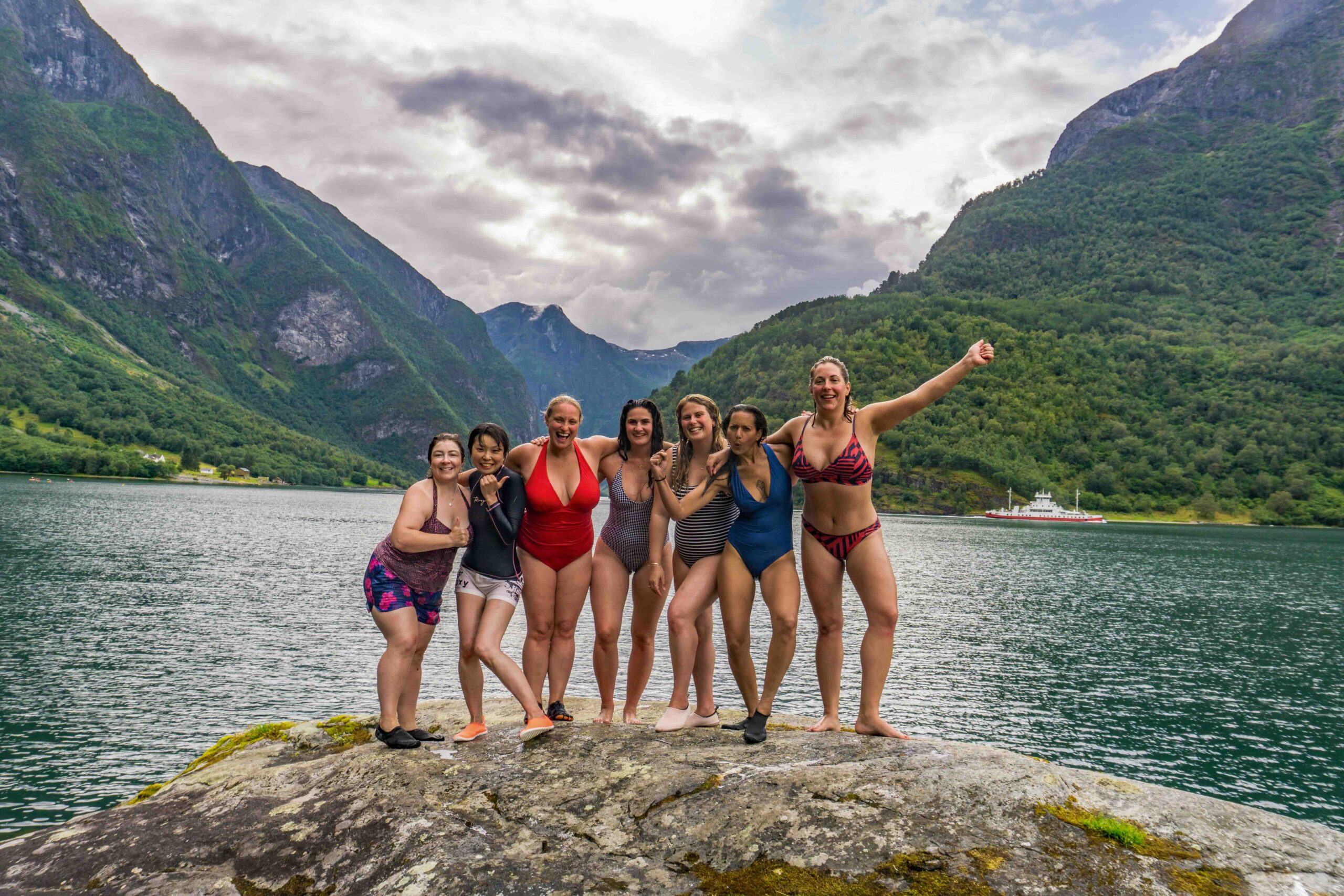 Women in swimsuits posing on a rock by a mountain lake in a valley