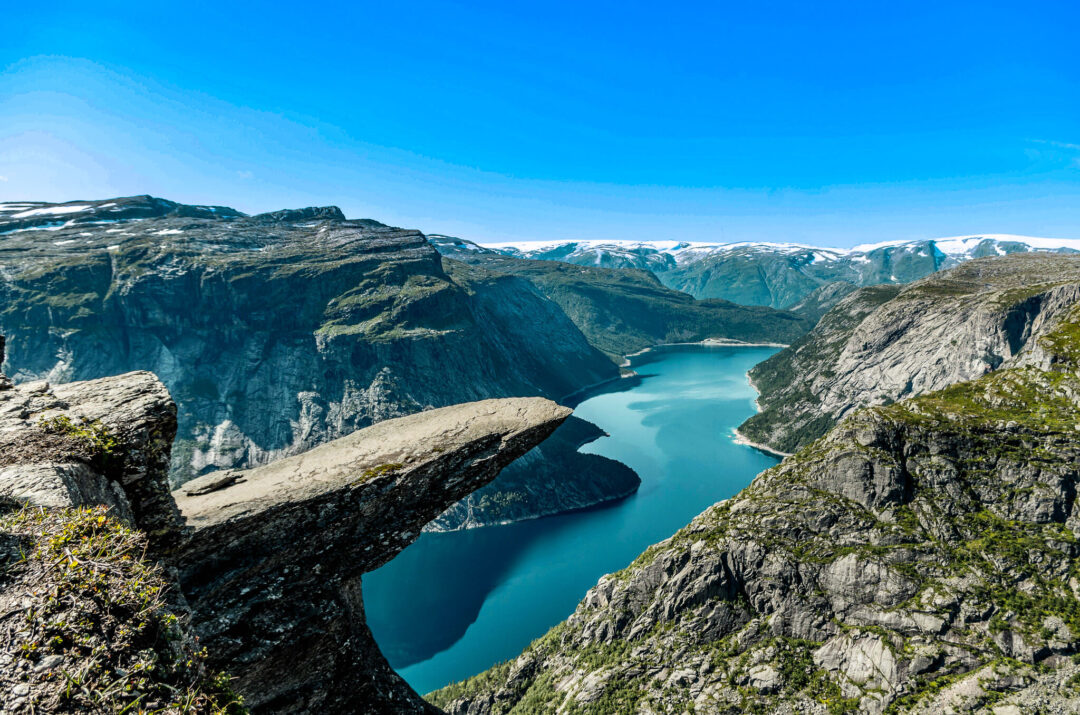 Norwegian fjord landscape with turquoise water, rocky mountains and glacier snow under a clear blue sky