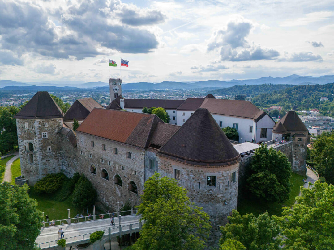 Ljubljana Castle in Slovenia seen from above, with flags flying over the courtyard