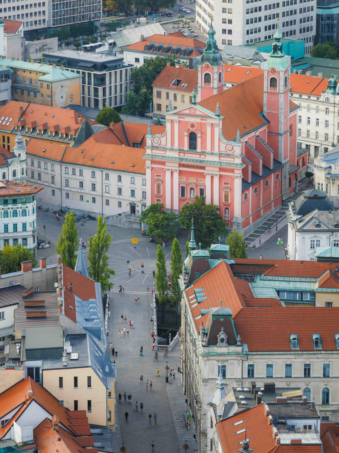 Ljubljana Old Town street view with a pink baroque church and red-tiled rooftops