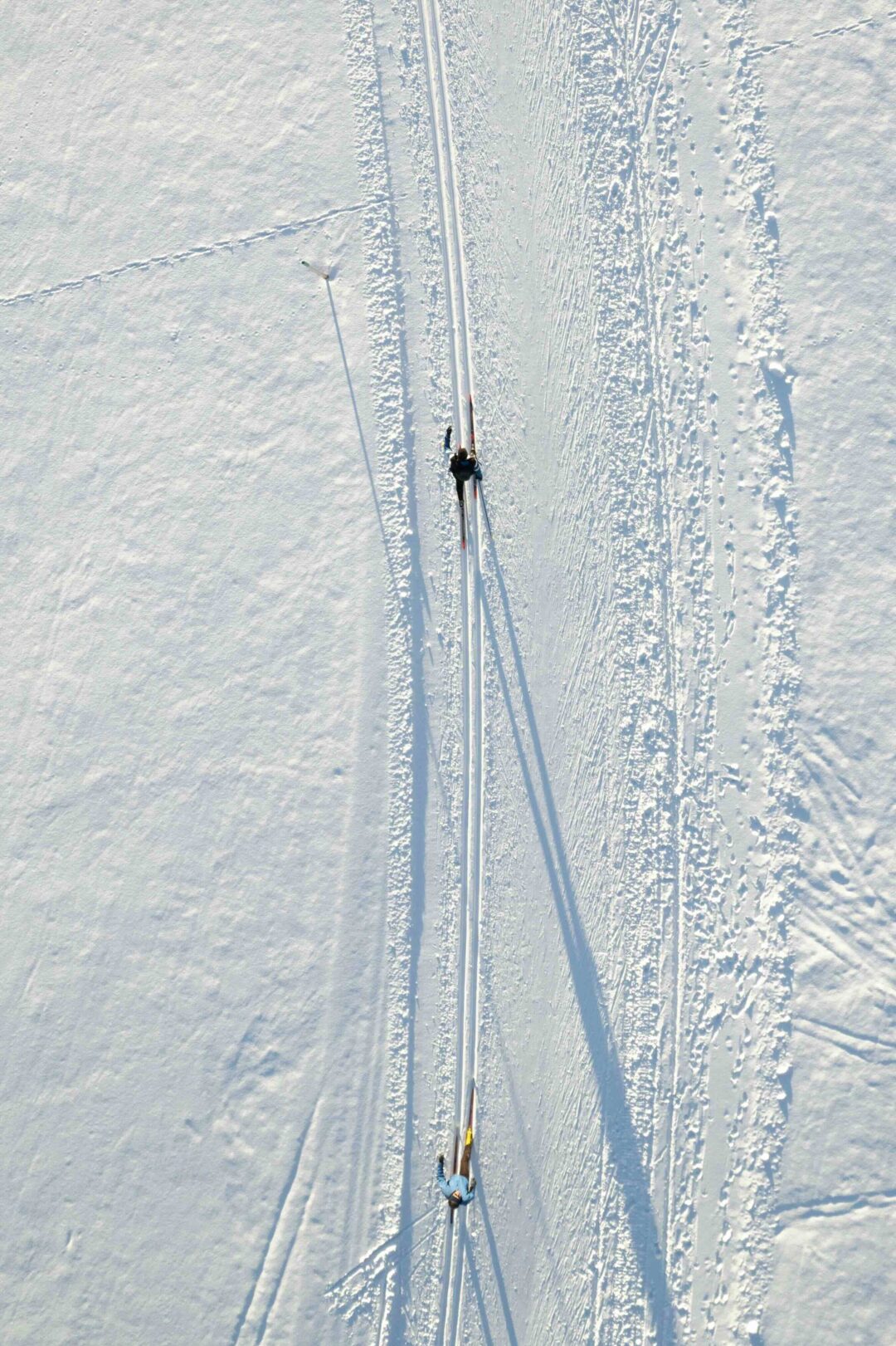 Cross-country skier gliding on skis through snowy tracks in spring conditions