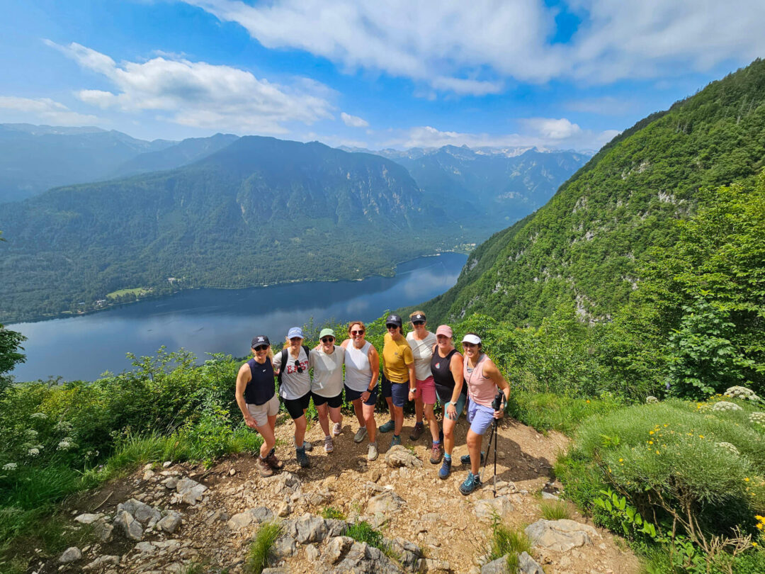 Women hiking on a trail with a lakeside valley view in Slovenia’s mountains