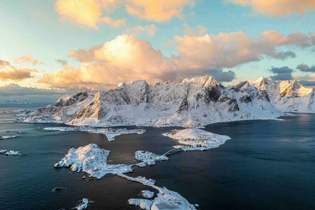 Snowy Arctic coastline with glaciers and mountains at dusk, viewed over the sea in northern Europe
