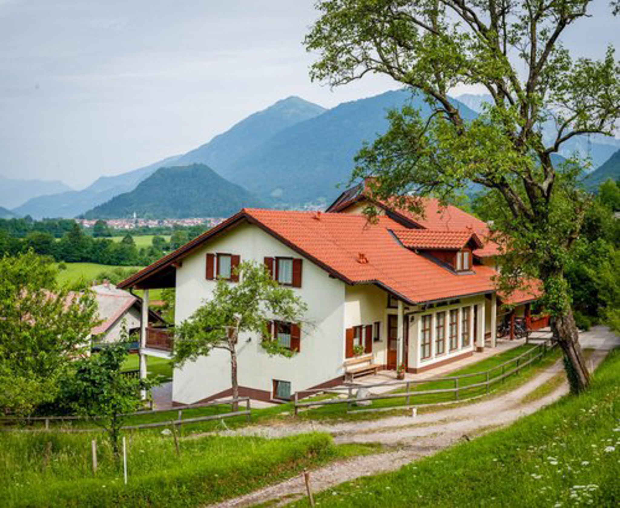 Rural guesthouse in the Slovenian countryside with red-tiled roof, green fields and mountain views