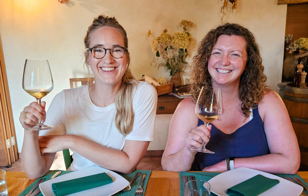 Women wine tasting indoors in Slovenia, smiling and holding glasses at a table
