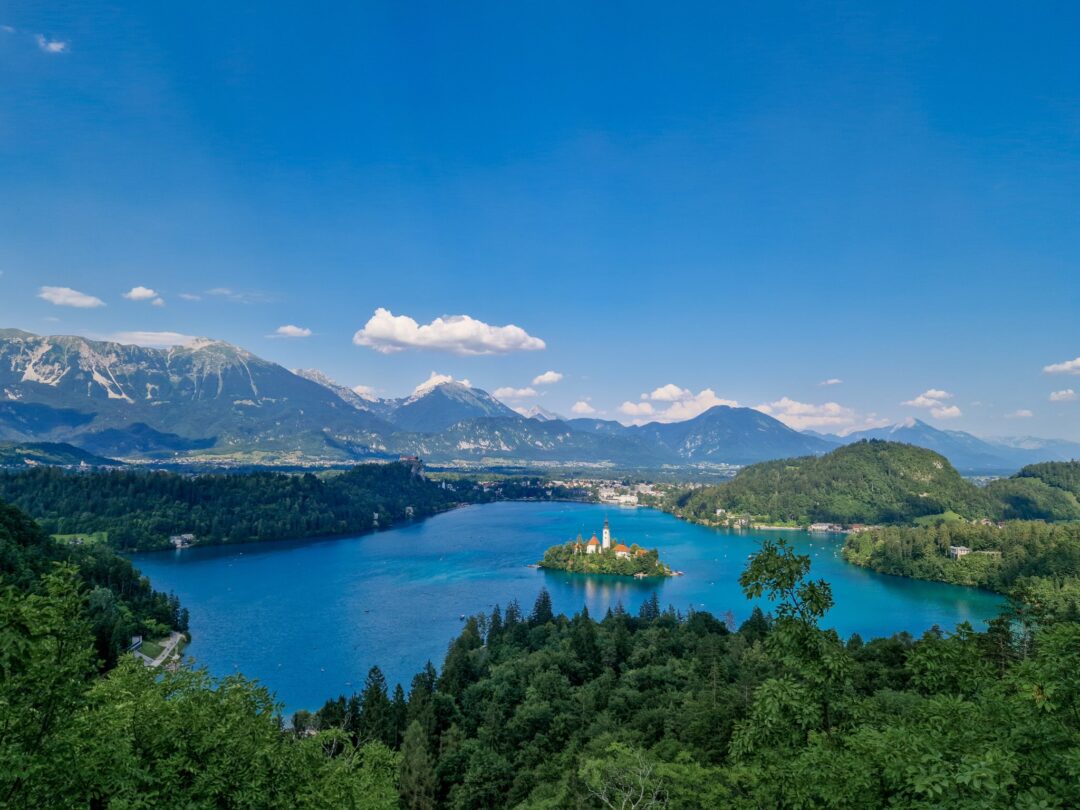 Lake Bohinj in Slovenia with island church and mountain views from the forested hills.