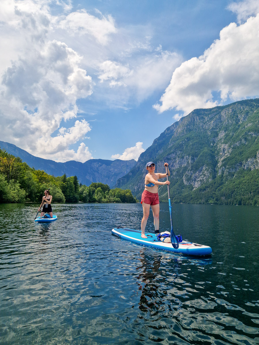 Women paddleboarding on a calm lake with mountains in the background