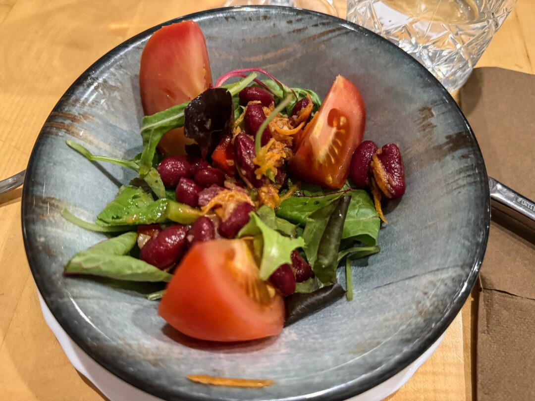 Woman’s plate of mixed salad with olives, tomato and vegetables on a table during an outdoor holiday in Slovenia
