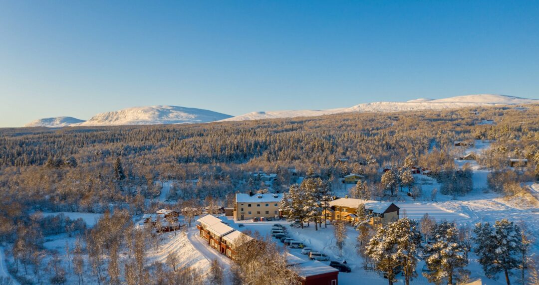 Winter aerial view of a ski resort village with snow-covered trees, slopes and buildings in the valley