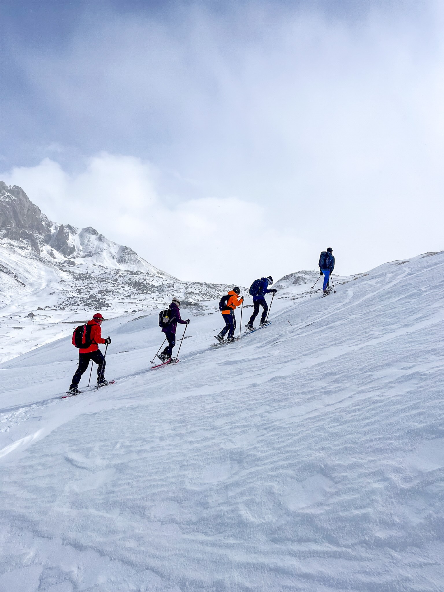 Women skiing downhill on a snowy mountain slope in winter, with skis and ski poles.