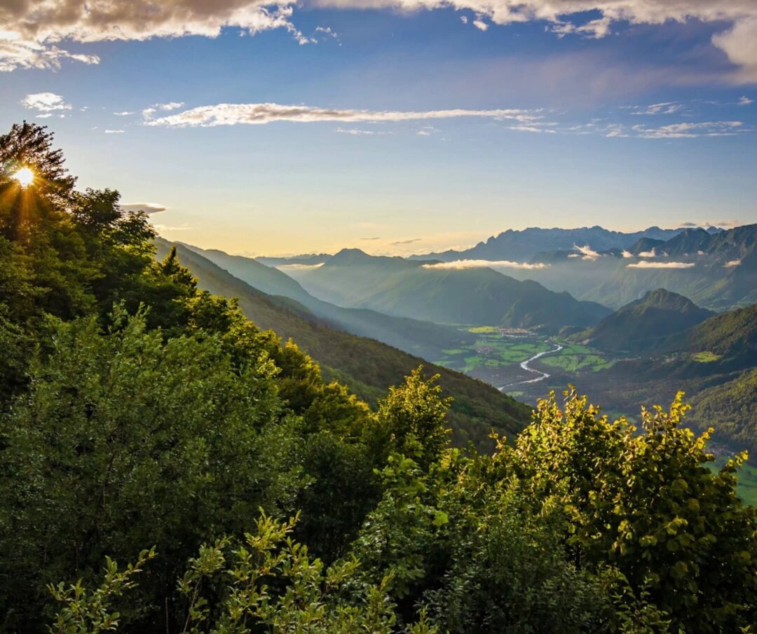 Scenic mountain valley at sunrise in Slovenia, with forested slopes and a winding river below