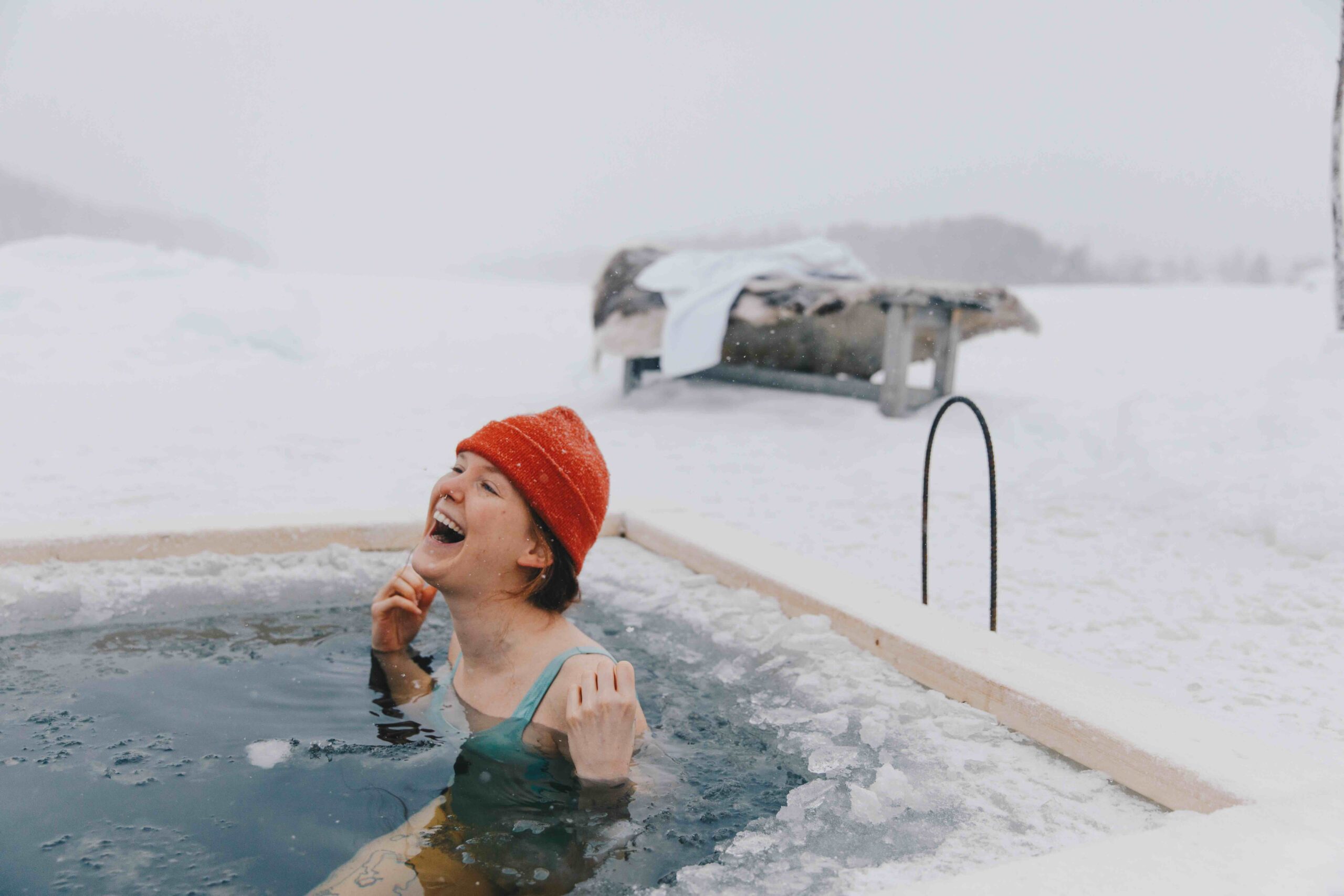 Woman soaking in a snowy outdoor hot tub in Swedish Lapland, with a frosty view and steam in winter air