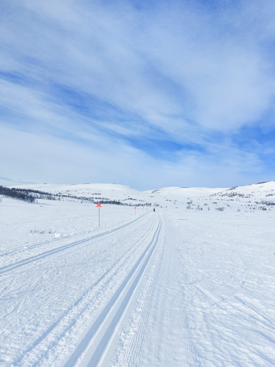Snowy skiing track winding through a winter landscape under a blue sky