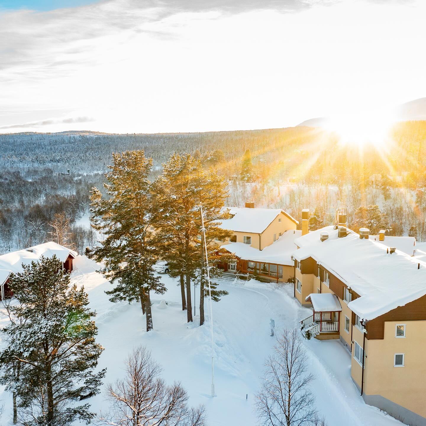Snow-covered village buildings and trees in a winter landscape at sunset