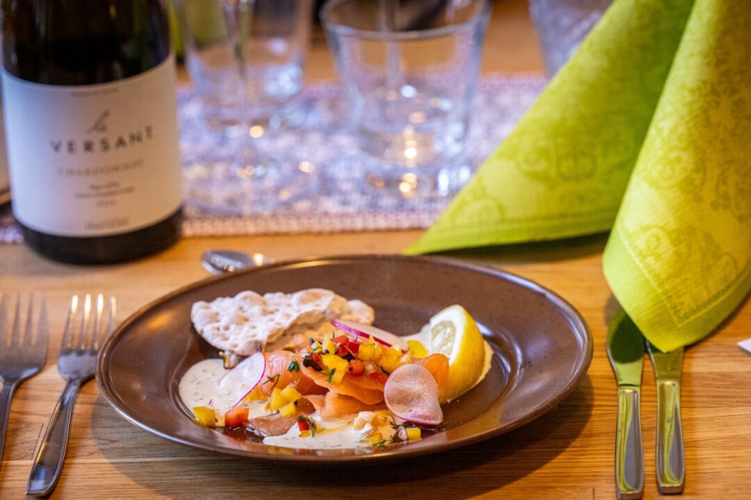 Plate of sliced fruit with yoghurt and a lemon wedge on a table, with green napkins.