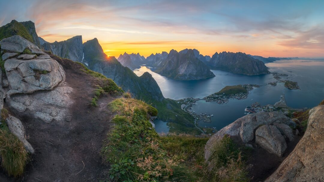 Scenic mountain hike viewpoint over Norway’s fjord at sunrise, with rocky cliffs and misty sea