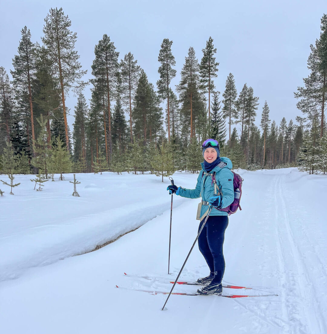 Female cross-country skier on skis in snowy pine forest, Finland winter trail.