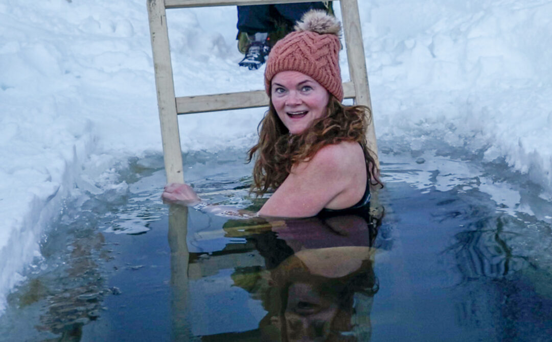 Woman in a winter hot tub in Sweden, cross country ski day, wearing a pink bobble hat