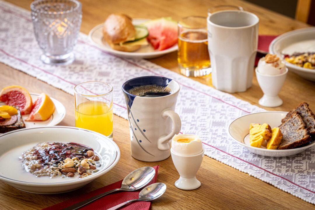 Swedish breakfast table with coffee, juice and hearty dishes on a cosy wooden setting
