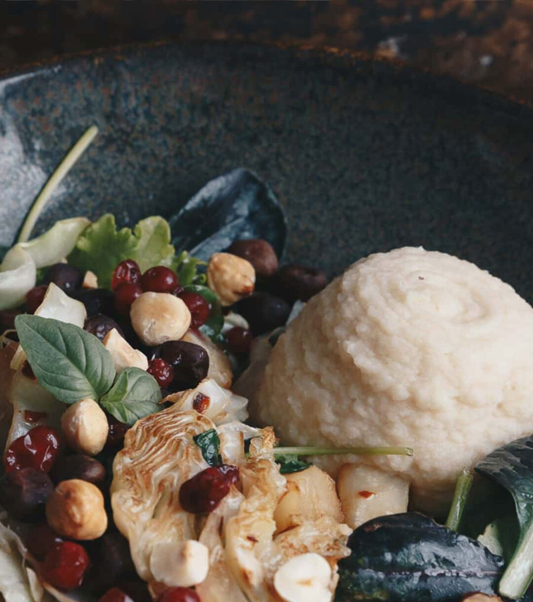 Bowl of winter vegetarian salad with roasted vegetables, mushrooms, greens and creamy white cheese