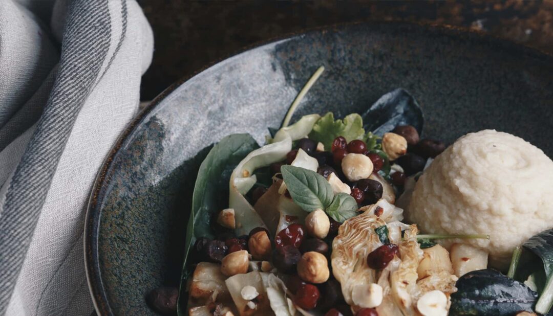 Hearty Swedish-style meal in a dark bowl, with chicken, mushrooms, cranberries and vegetables