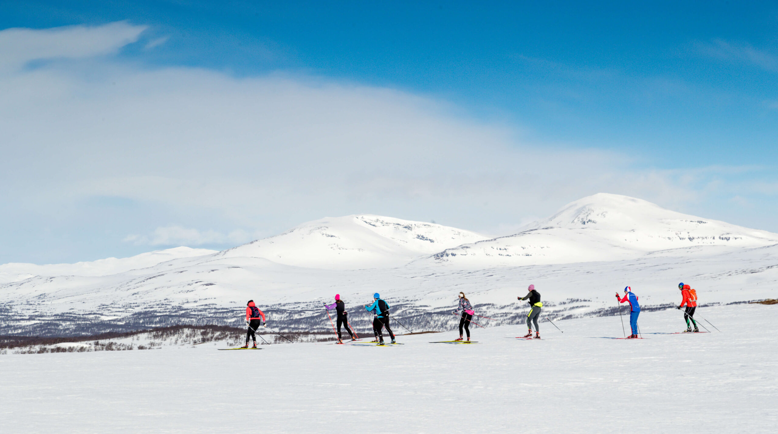 Women cross-country skate skiers training on a snowy mountain slope in Sweden
