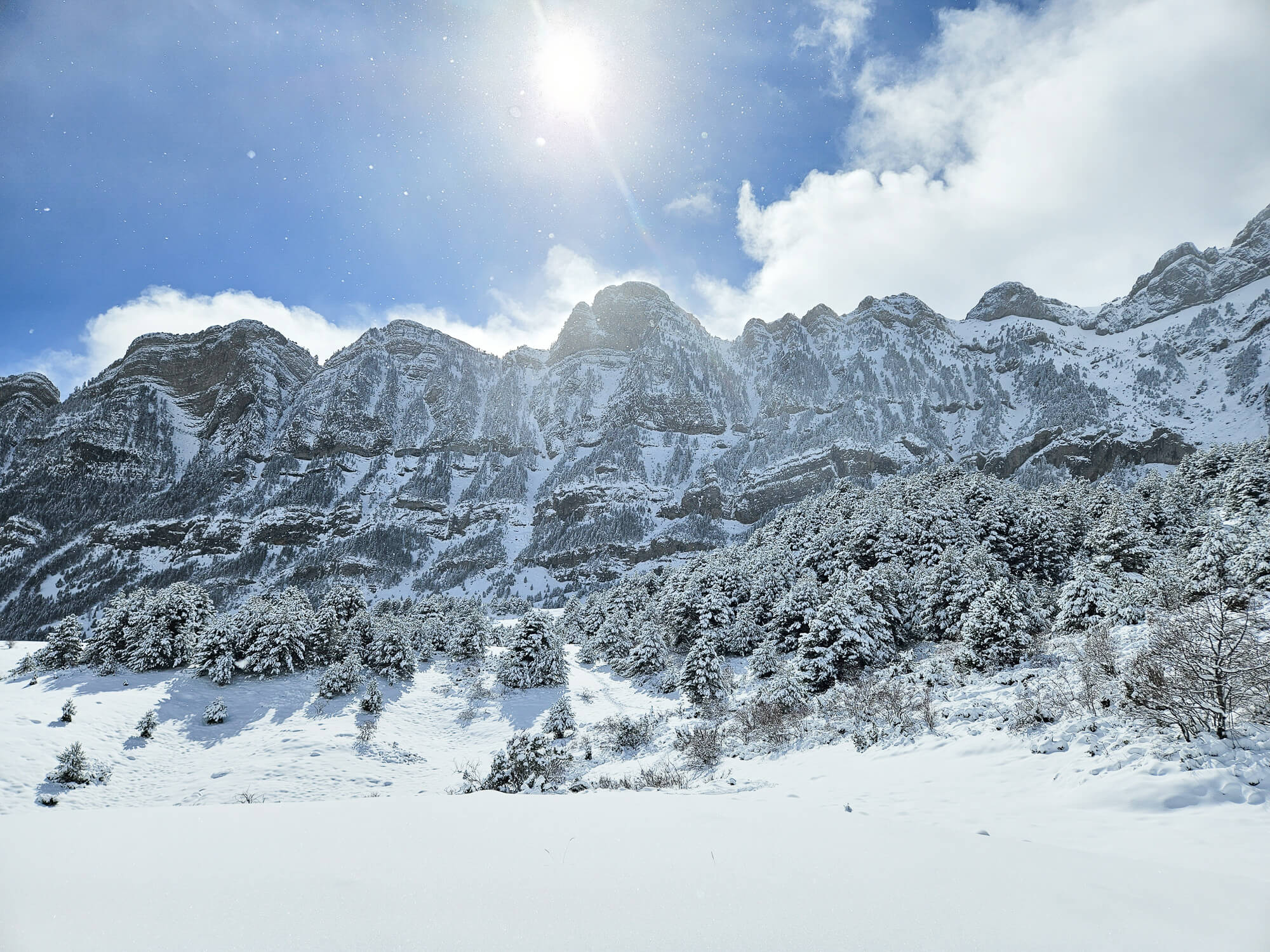 Snow-covered Pyrenees mountains and winter hiking valley under bright sun, clear blue sky