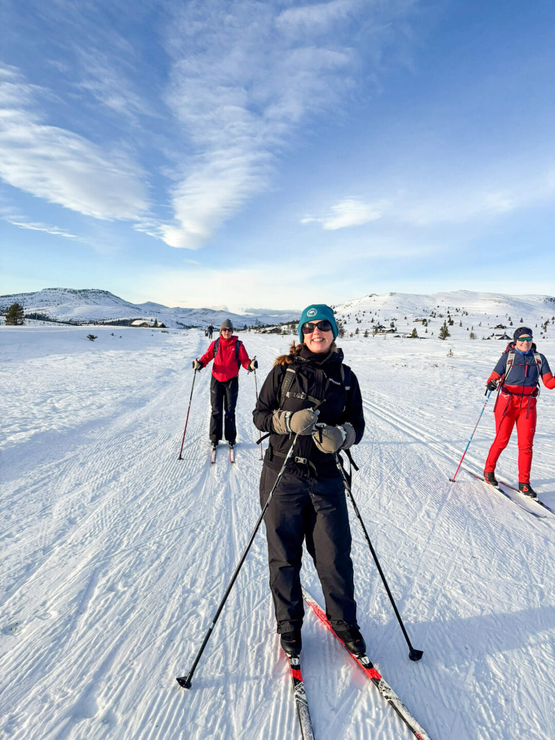 Women cross-country skiing on snow-covered slopes with mountains and lake in Norway
