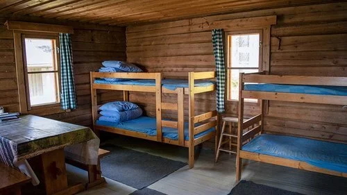 Bunk room inside a Finnish wilderness cabin, with wooden bunks and sleeping mattresses for snowshoeing adventures