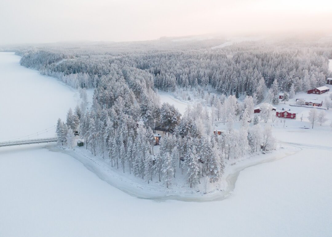 Snowy forest valley with cabins and a frozen river in Swedish Lapland