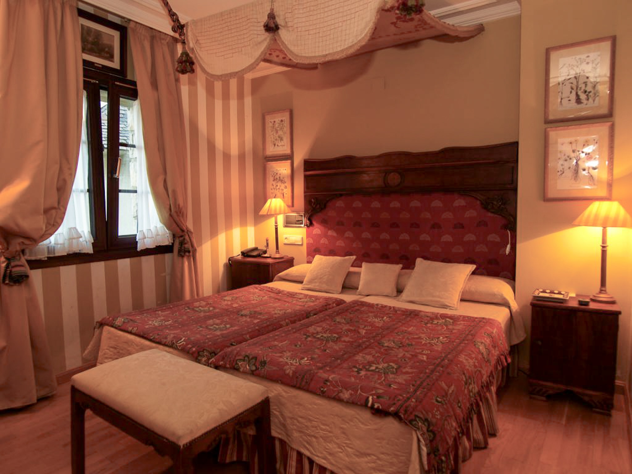 Cozy bedroom with double bed, red patterned bedspread and bedside lamps in a country house