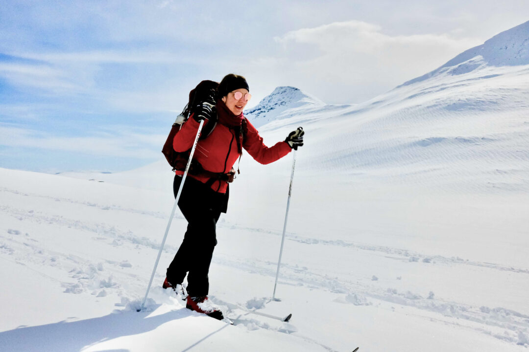 Woman ski touring in a snowy mountain landscape, wearing winter jacket and using trekking poles
