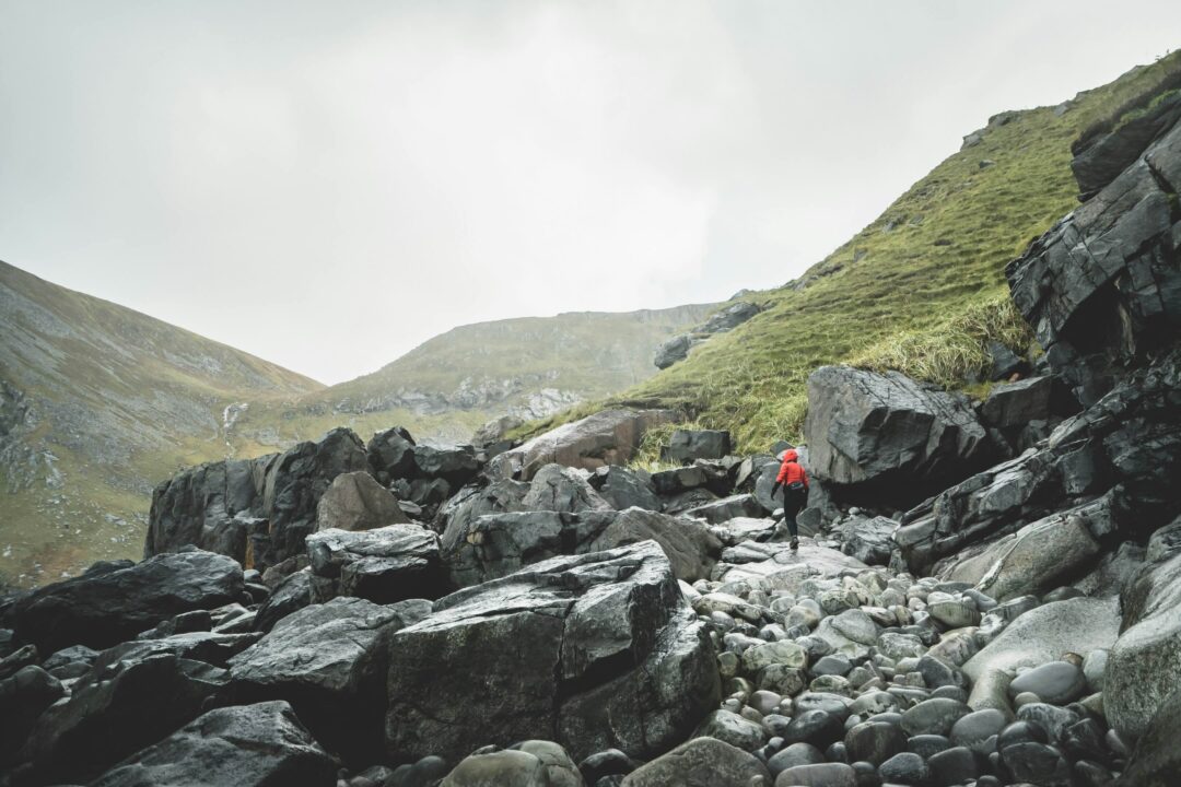 Woman hiking on a rocky mountain trail through a misty valley