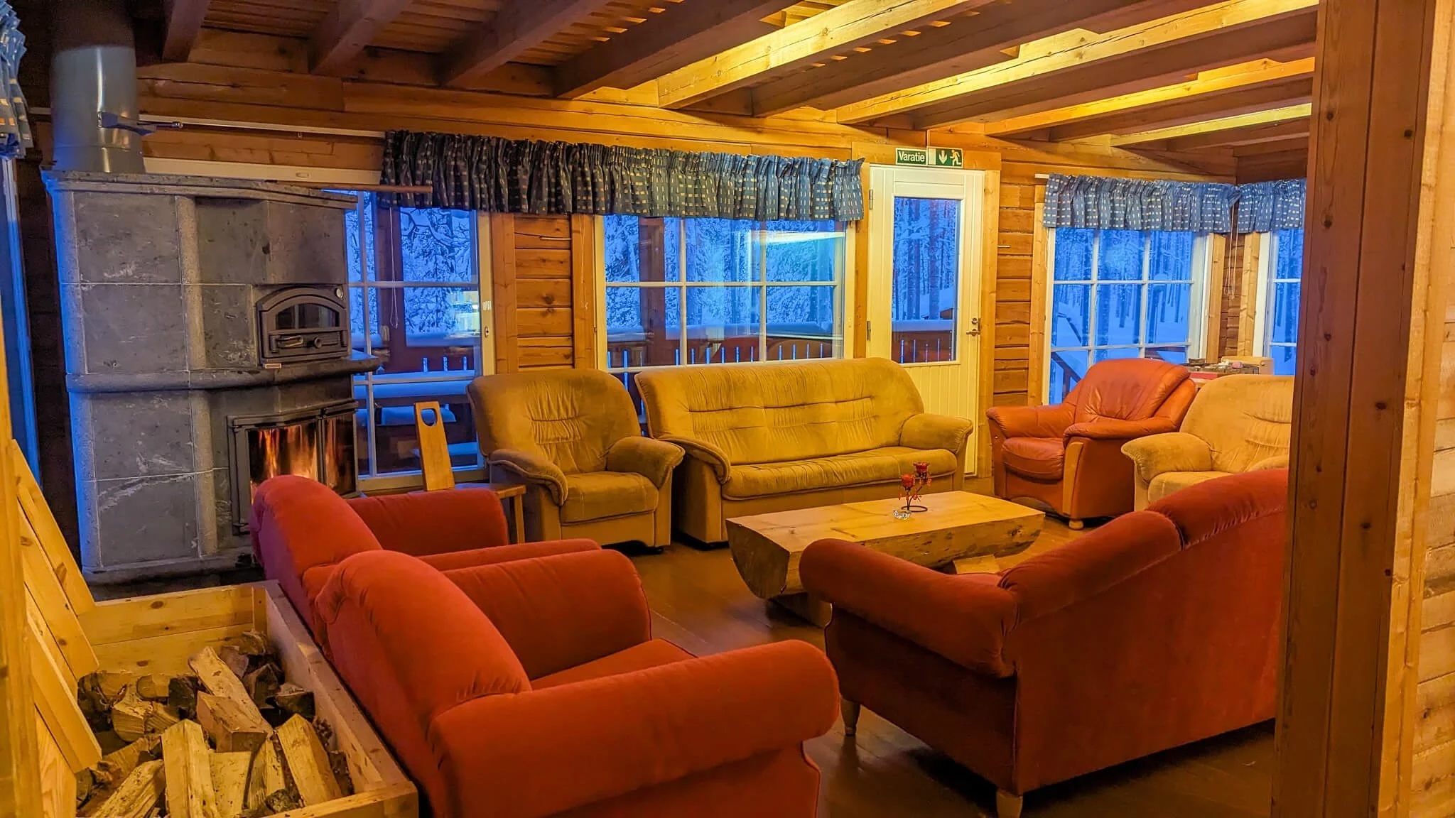 Cozy Finnish wilderness cabin living room with orange sofas and snow-covered view through large windows
