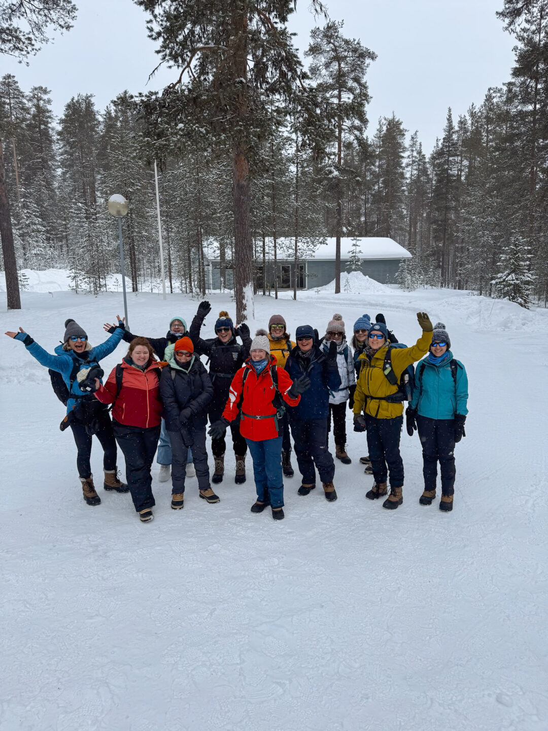 Group of snowshoe hikers in winter gear posing in a Finnish forest clearing after snowshoeing