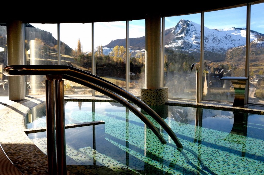 Indoor heated pool with glass view to snowy Pyrenees mountains, ideal for winter hiking in the Pyrenees