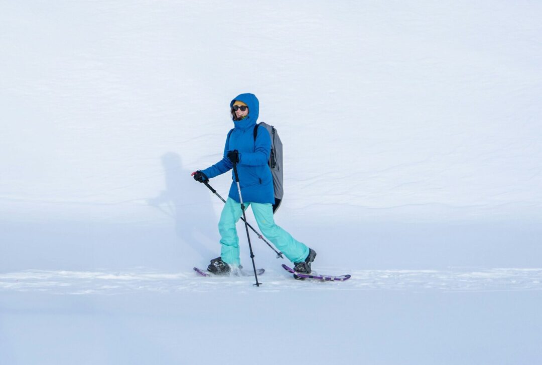 Woman skiing across a snowy landscape, wearing goggles, ski poles and skis.