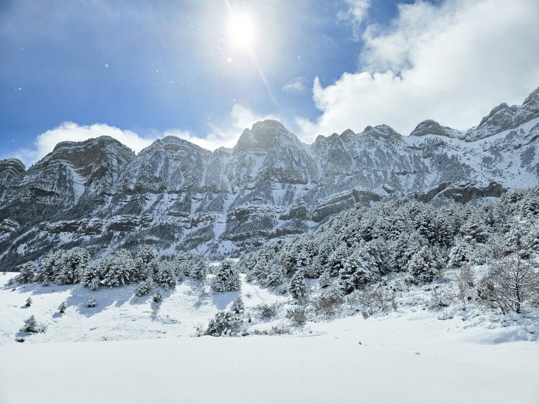 Snowy Pyrenees mountain landscape for winter hiking, with snow-covered peaks and valley under a blue sky