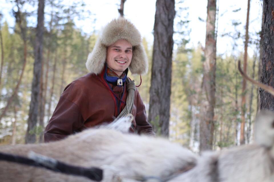 Smiling winter adventurer in a fur hat and coat in a snowy Lapland forest, outdoors in cold weather