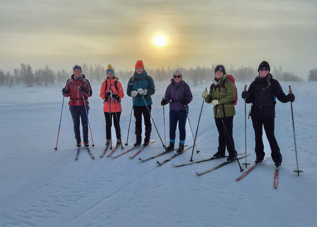 Group of beginner cross-country skiers in winter gear at dawn, skis on snowy Norway trail