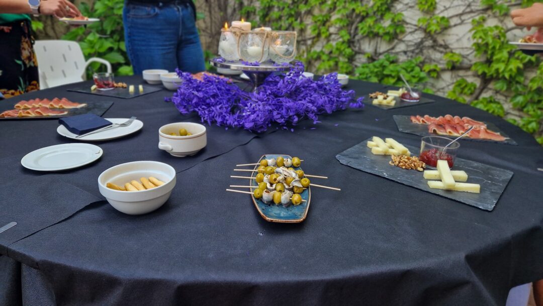 Outdoor picnic table set with appetisers, olives and floral decorations in a garden