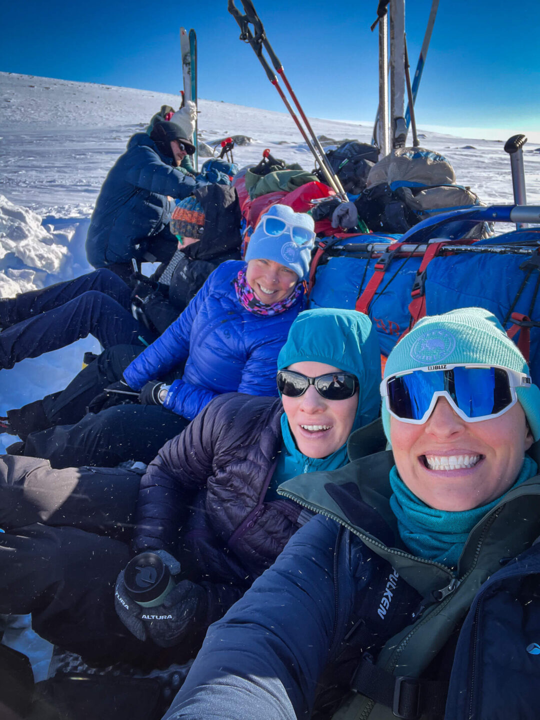Smiling skiers in an Arctic hut-to-hut expedition, packed on snow with skis and trekking poles