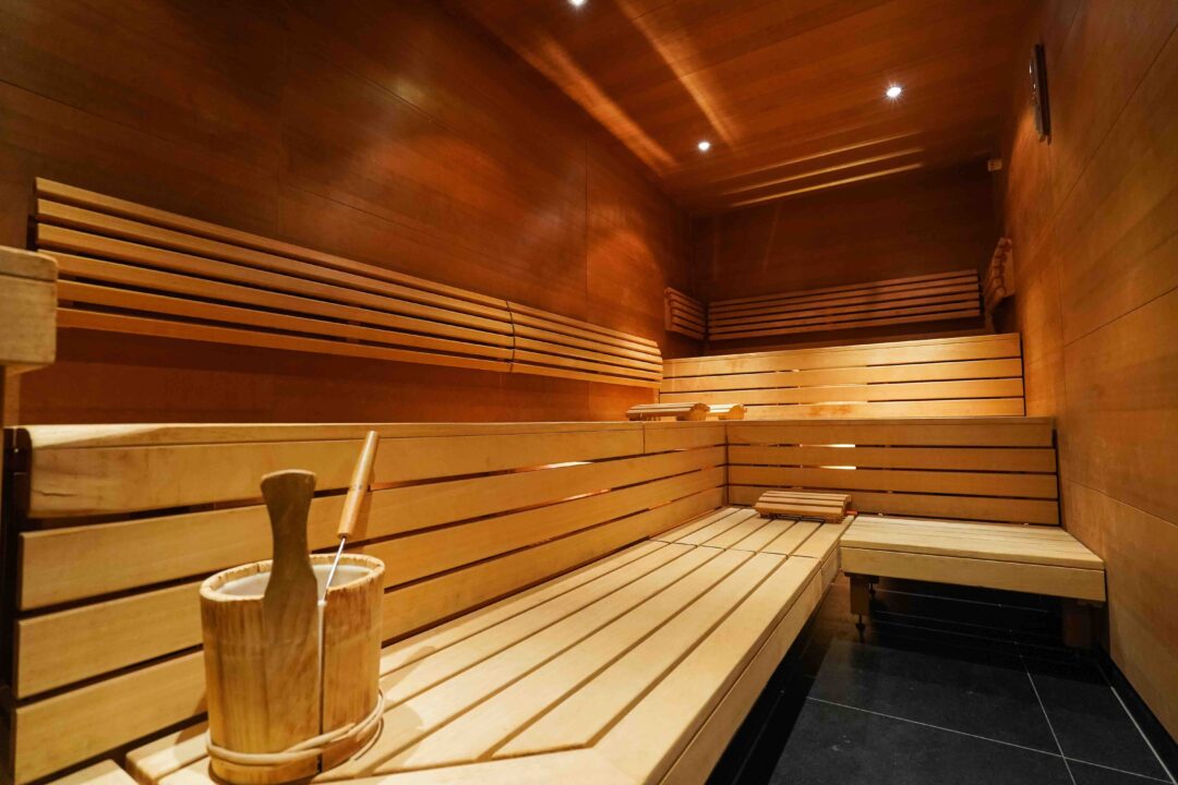 Indoor wooden sauna with bench seating and stove, warm relaxing wellness space for a hike and kayak adventure