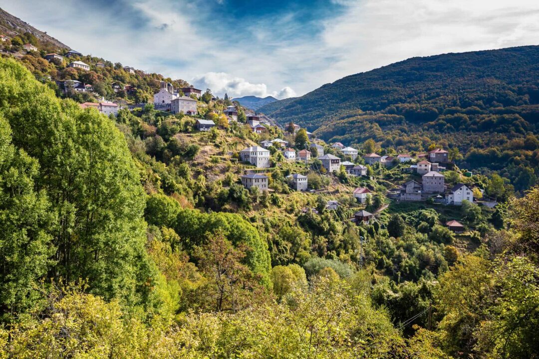 Scenic hillside village in a mountain valley with lush green forests, suitable for guided hiking in North Macedonia