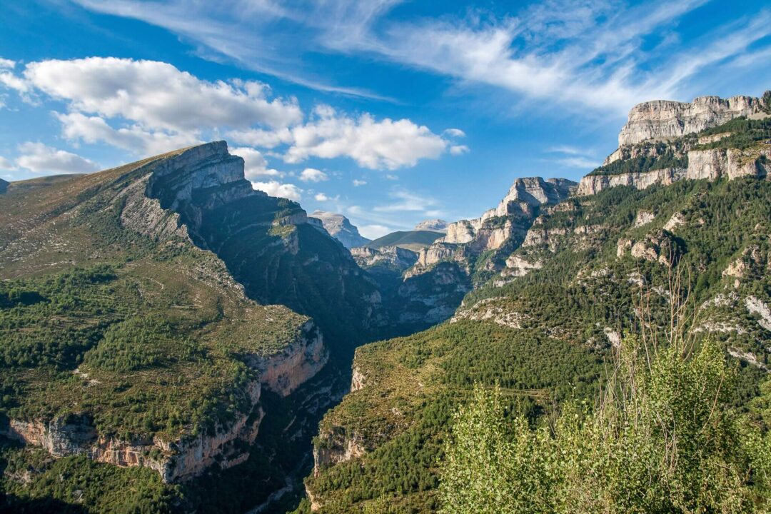 Mountain valley landscape with rugged peaks and forested slopes, suited for hiking holidays