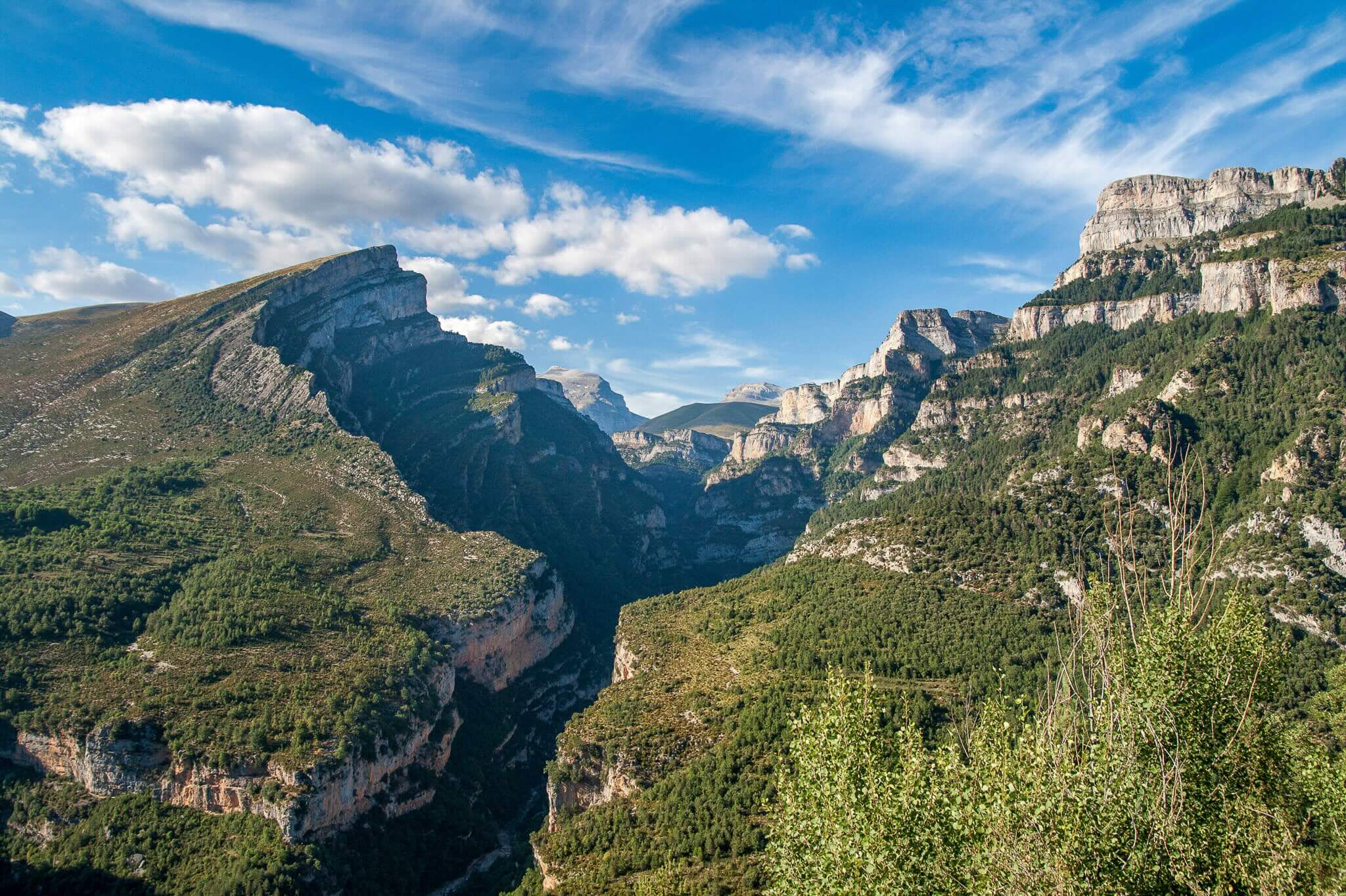 Mountain valley landscape with rugged peaks and forested slopes, suited for hiking holidays